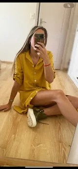 Vestido camisero midi color verde oliva, con cuello clásico, mangas cortas con trabillas y botones dorados, y cierre frontal con botones dorados.