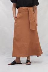 Falda midi color marrón de lino con bolsillos laterales y volante en el ruedo. Tiene una tira en la cintura para anudar en la delantera.