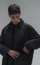 Campera oversize de microfibra opaca con diseño matelaseado de rombos. Presenta cuello de corderoy a tono, cierre frontal metálico y dos amplios bolsillos delanteros con solapa y broche snap. Interior forrado y relleno con guata térmica.