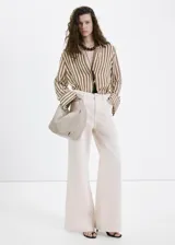 Jeans de algodón estilo wide leg en color beige, con diseño de tiro medio, cinco bolsillos, trabillas para cinturón y cierre frontal con botón y cremallera.