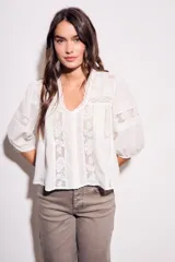 Blusa negra de algodón peinado con calce oversize, escote en V, mangas tres cuartos abullonadas y detalles de encaje y bordados en el frente y mangas.