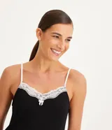 Camisón corto negro de viscolycra, con breteles finos blancos y escote en V decorado con encaje blanco y un pequeño lazo al centro. Presenta detalles de encaje blanco en el ruedo.