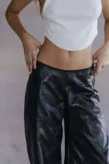 Pantalón cargo de ecocuero negro, de corte holgado y tiro medio-alto. Presenta bolsillos laterales tipo cargo y costuras visibles a lo largo de las piernas.