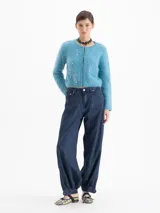 Cardigan de tejido de punto suave en color azul, con cuello redondo, cierre frontal y manga larga. Presenta pequeños apliques metálicos en forma de corazón distribuidos por toda la prenda.