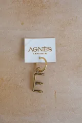 Arete tipo argolla de metal color bronce con dije colgante de la letra "E" en estilo rústico. Se vende por unidad.