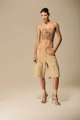 Bermuda estilo cargo color beige, de tiro bajo, con grandes bolsillos laterales con solapa y cierres metálicos.