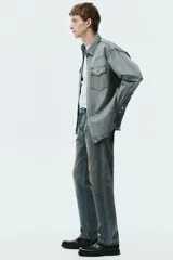 Pantalón jean de cinco bolsillos en denim de algodón rígido, con pierna recta apenas holgada y corte estándar. Cuenta con cintura clásica y cierre de botones.