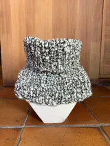 Cuello tejido a mano en lana merino color crudo, con textura acanalada y aberturas laterales.