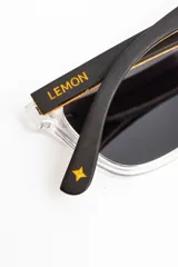 Lentes de sol polarizados con armazón transparente y patillas de madera, con cristales oscuros.
