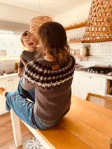 Sweater de punto color gris con guarda pampa en blanco y negro en la parte superior.