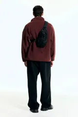 Buzo deportivo de polar color bordó, con cuello alto y cierre frontal parcial. Presenta mangas largas de corte caído y bolsillos laterales integrados en la costura.
