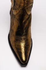 Bota alta estilo cowboy color dorado metalizado, con bordados decorativos y puntera en punta.