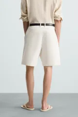 Bermuda de corte regular fit, color blanco hueso, confeccionada en tejido de algodón y lino. Presenta pliegues frontales, bolsillos delanteros y bolsillos traseros de plastrón.