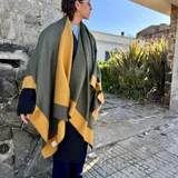 Ruana de material símil cachemira, de diseño bicolor en tonos gris y lila con bandas anchas en los bordes.