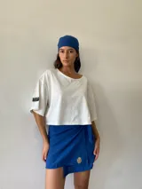 Conjunto compuesto por un pareo corto de color azul con detalle de bordado dorado en el frente y una bandana a juego. El pareo cuenta con un diseño envolvente con lazo lateral.