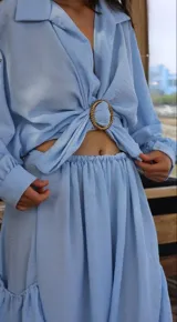 Conjunto de dos piezas compuesto por una camisa de mangas largas y un pantalón tipo babucha con ajuste en la cintura y tobillos, con bolsillos laterales amplios. El diseño incluye un detalle de hebilla circular en la cintura.