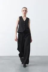 Pantalón wide leg negro de tiro alto con caída fluida y silueta amplia. Presenta cintura alta con botonadura frontal visible.