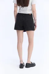 Short pollera de jean negro, con diseño cruzado asimétrico en el frente, bolsillos y tiro alto.