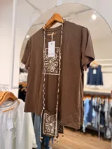 Remera marrón de manga corta y cuello redondo, con estampado floral en un recuadro claro en el frente.