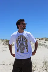 Remera oversize color marrón claro con estampado frontal de un paisaje desértico con palmeras y un camello.