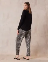 Conjunto de pijama marca René Rofé, compuesto por remera negra de manga larga con bolsillo en el pecho y pantalón largo con estampado animal print, cintura elastizada y lazo de ajuste.