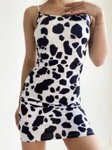 Vestido corto ajustado al cuerpo, con tirantes finos y escote redondo, estampado de manchas de vaca (blanco y negro).