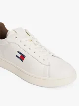 Zapatillas de estilo tenis confeccionadas en piel napa blanca, con diseño de corte bajo y cordones. Presentan un panel a contraste en el talón en color marrón y el parche distintivo de Tommy Jeans en el lateral.
