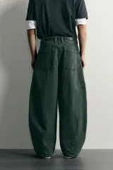 Pantalón barrel fit de mezclilla color verde militar, con efecto lavado, cinco bolsillos, cierre frontal con cremallera y botón, y detalle de pinzas en las rodillas.