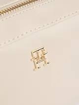 Cartera bandolera de poliuretano color beige, de diseño estructurado con compartimento principal con cierre, bolsillo interior y correa ajustable. Cuenta con el logo metalizado de la marca en el frente y detalles dorados.