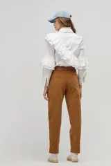 Camisa blanca de popelina de algodón con cuello clásico y botones de nácar. Presenta volados dobles decorativos que recorren el frente y la espalda desde el hombro hasta la cintura, además de volados en las mangas a la altura del codo.