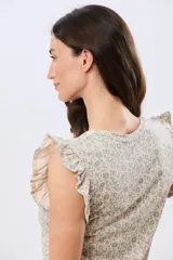 Musculosa blanca con estampado floreado sutil y volados en los hombros, de corte recto.