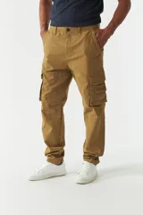 Pantalón cargo color marrón claro, de corte regular, con bolsillos laterales con fuelle y cierre de botón.