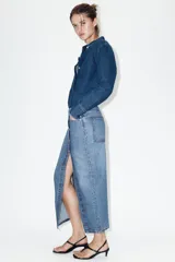 Falda midi de denim azul con diseño cruzado, cierre frontal con botones metálicos y bolsillos delanteros.