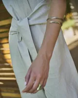 Brazalete rígido de diseño minimalista con forma de espiral, elaborado artesanalmente en bronce y alpaca maciza. Es una pieza ajustable que puede lucirse tanto en el antebrazo como en la parte superior del brazo.