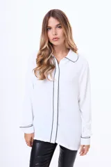 Camisa blanca de manga larga con cuello clásico y detalles de ribete en color negro en el cuello, la botonadura frontal y los puños.