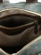Mochila Hush Puppies modelo Saba de cuero color marrón con efecto avejentado, asa superior y tiras de flecos decorativos en los cierres laterales.