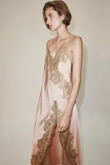 Vestido largo tipo lencero de Zara Woman Collection, confeccionado en tejido satinado color rosado con escote en pico y tirantes finos. Presenta detalles de aplicaciones de encaje a contraste y bajo asimétrico.