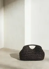 Bolso de mano de fibra natural trenzada en color marrón, con diseño estructurado de tamaño pequeño y asas integradas.