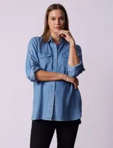 Camisa celeste de tencel con cuello con solapa, abertura central con botones ocultos, bolsillos delanteros y mangas largas regulables con presilla y botón.