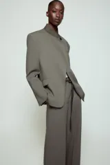 Blazer de corte estructurado en color verde oliva, con cuello subido en tejido a contraste de textura aterciopelada. Presenta cierre frontal con un solo botón, bolsillos con solapa en el delantero y un bolsillo superior tipo ojal.