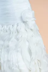Vestido de novia blanco de organza, con corset drapeado, falda con volados y cola larga. Presenta un delicado bordado de perlas en la cintura.