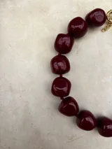 Collar de diseño artesanal compuesto por múltiples hileras de cuentas de resina pulida en una paleta de colores vibrantes que incluye tonos marrones, grises, verdes, naranjas y bordó.