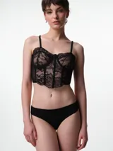 Corset de encaje negro con copas, aros y ballenas estructurales. Presenta breteles elásticos ajustables y un diseño que realza la silueta.