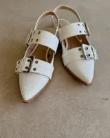 Chatas de cuero vacuno color negro, con punta fina, tira sobre el empeine con hebilla metálica y tira trasera con elástico.