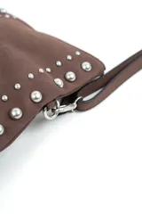 Cartera bandolera marrón decorada con tachas metálicas plateadas en los laterales y en dos líneas verticales frontales, con correa ajustable y cierre superior.