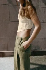 Top crop de punto color beige con escote en pico y tirantes finos ajustables. Presenta diseño con tejido calado y bajo de acabado asimétrico.
