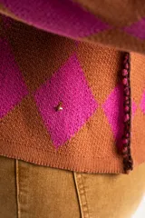 Sweater de punto con diseño de rombos en colores fucsia y tostado, cuello redondo y mangas largas.