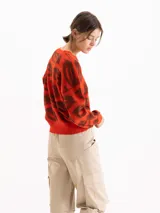 Sweater tejido semi pesado color rojo con estampado de labios en marrón, de corte holgado, escote redondo y mangas largas con hombros caídos.