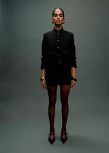 Chaqueta recta color negro con cuello mao, cierre frontal y bolsillos delanteros con solapa y botones joya.