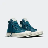 Championes Converse modelo Chuck 70 de caña alta, confeccionados en lona resistente con superposiciones de gamuza. Presentan suela de goma con acabado barnizado, puntera reforzada y el icónico parche de estrella en el lateral.